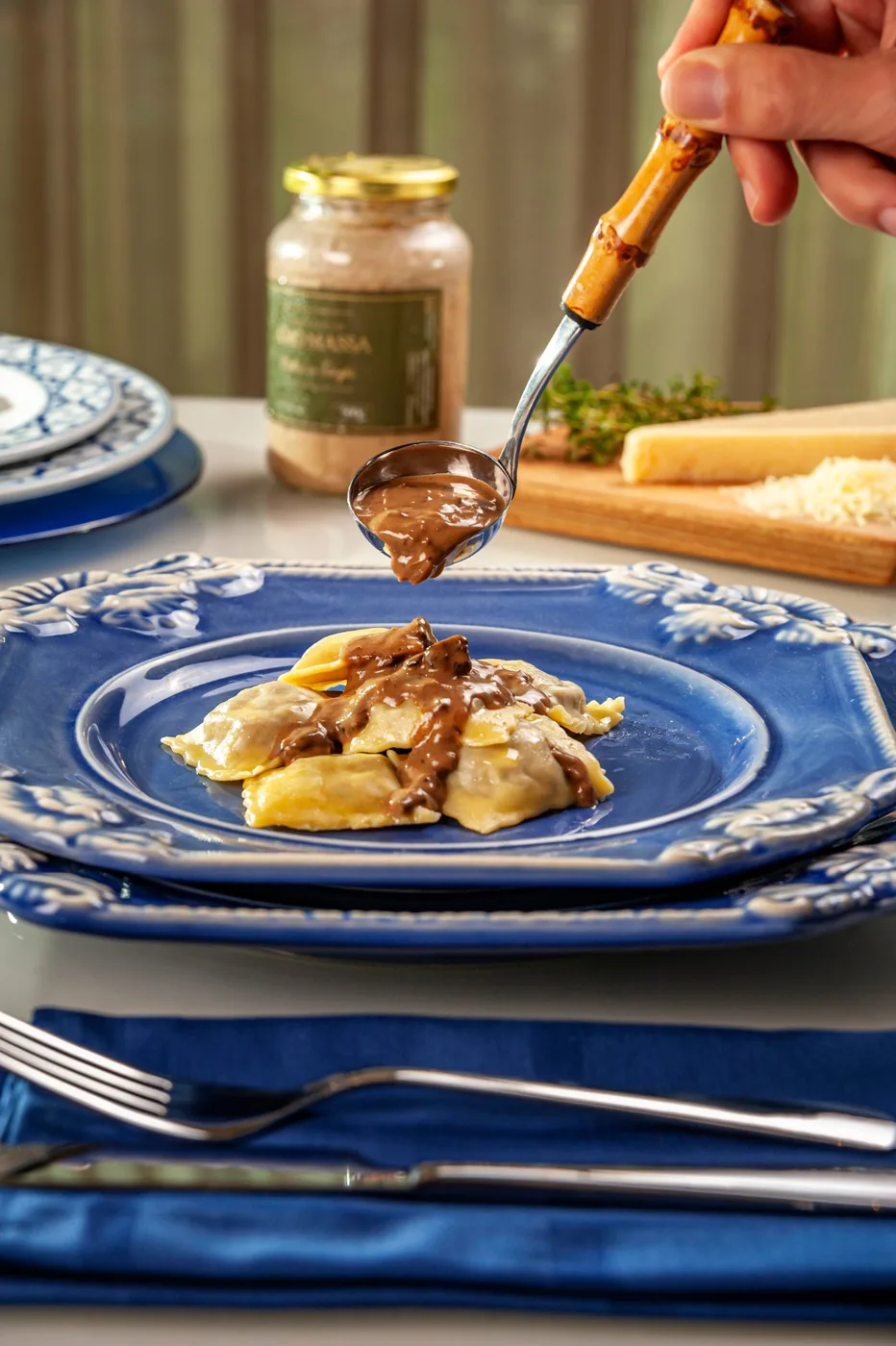 Molho de funghi sendo servido sobre ravióli em prato azul